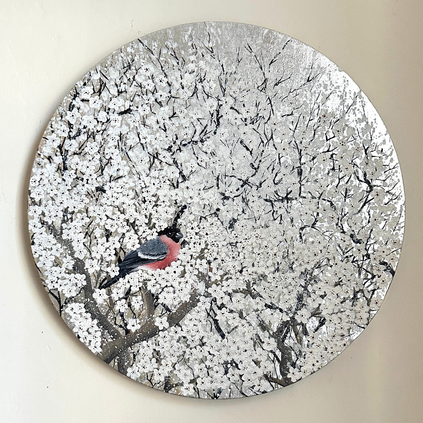 Round decorative piece with a bird on a branch with white blossom