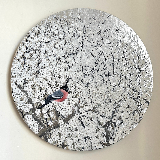 Round decorative piece with a bird on a branch with white blossom