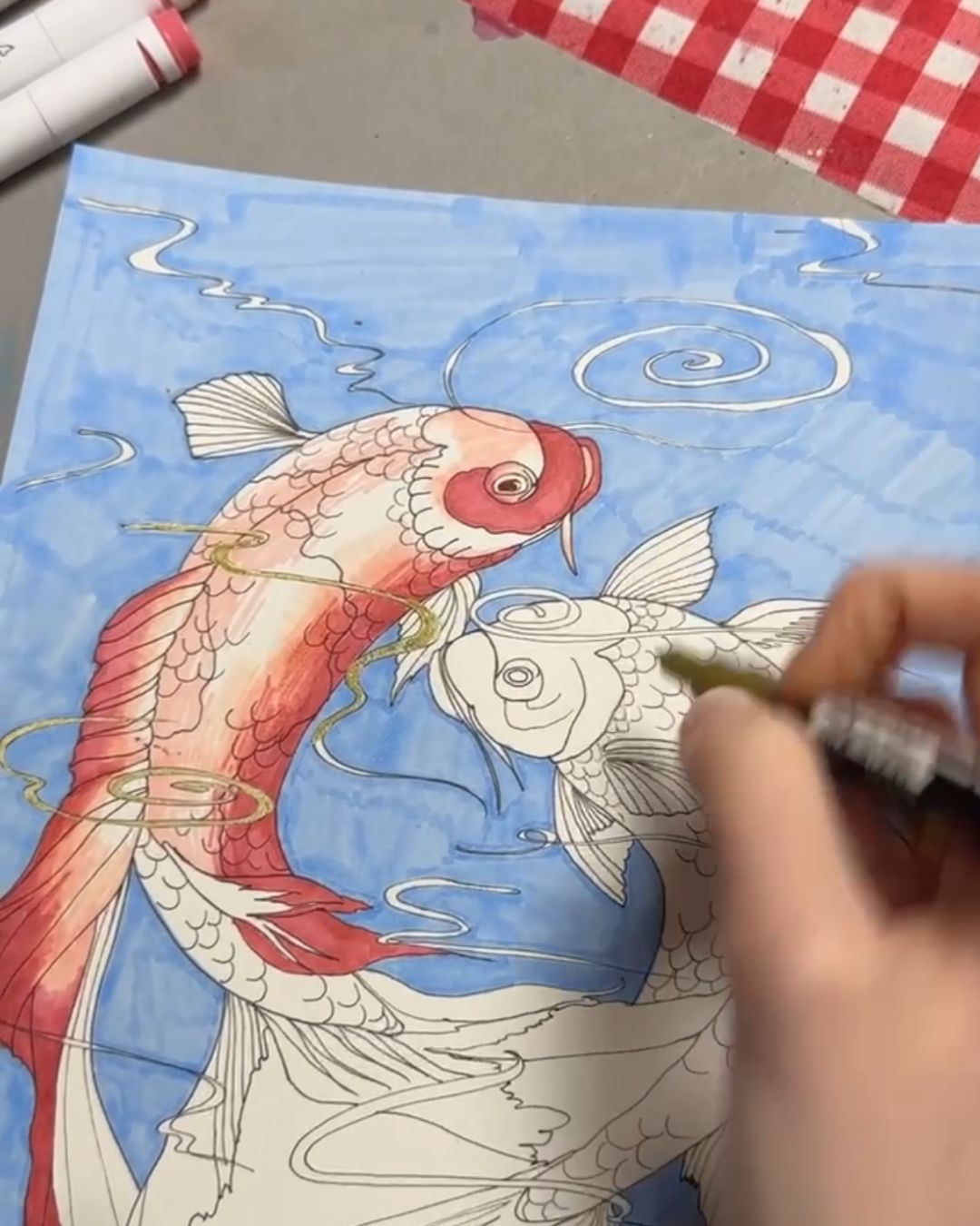 Work-in-progress photo of the koi fish illustration being coloured with markers